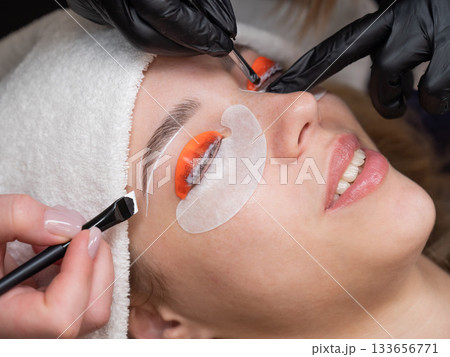 The process of professional lamination and dyeing of eyelashes and eyebrows in the salon. Four-handed procedure. The process of professional lamination and dyeing of eyelashes and eyebrows in the salon. Four-handed procedure. 133656771