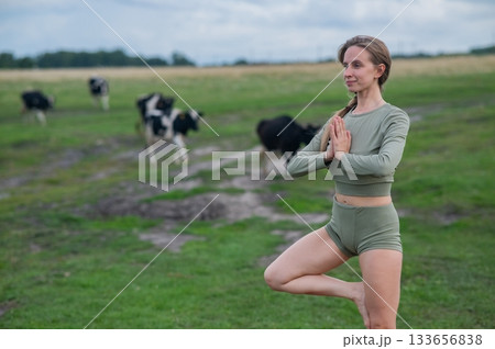 Caucasian woman doing yoga in rural area among herd of cows.  133656838