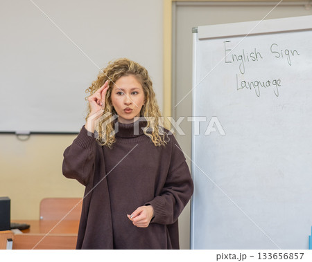 Caucasian female teacher communicates in Russian sign language with students. Caucasian female teacher communicates in Russian sign language with students. 133656857