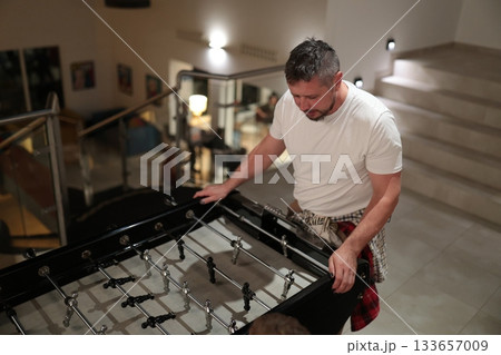 Adult man playing foosball game indoors 133657009