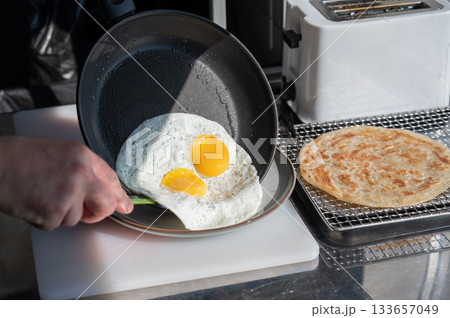 The chef fries the eggs sunny side up. The chef fries the eggs sunny side up. 133657049