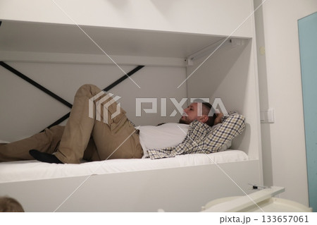 Man relaxing in modern compact guest bed Man relaxing in modern compact guest bed 133657061