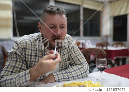 Man eating meal at restaurant table with wine Man eating meal at restaurant table with wine 133657071