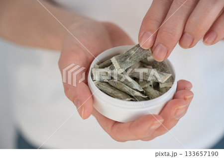 A woman holds a jar of chewing tobacco.  133657190