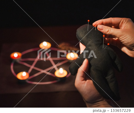 Woman sticking pins into voodoo doll.  133657229