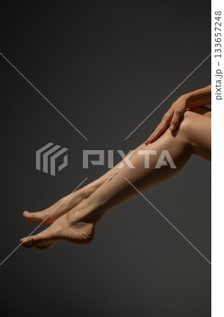 Woman applying moisturizer to her legs. Woman applying moisturizer to her legs. 133657248