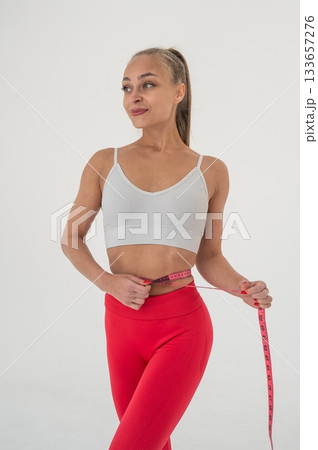 Young woman measuring her waist on white background. Young woman measuring her waist on white background. 133657276