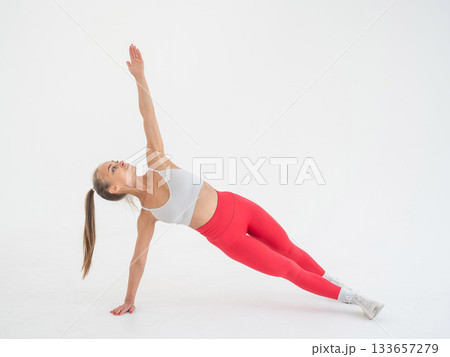 Young woman doing side plank on white background. 133657279
