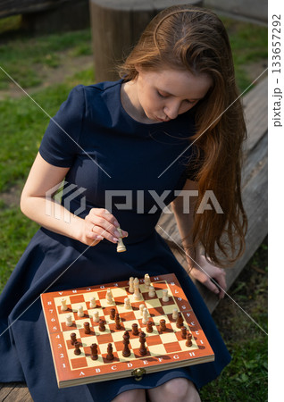 Caucasian woman playing chess outdoors. Caucasian woman playing chess outdoors. 133657292