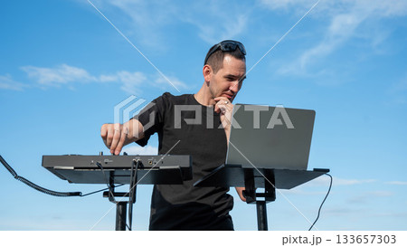 Male DJ playing music on the beach. Male DJ playing music on the beach. 133657303