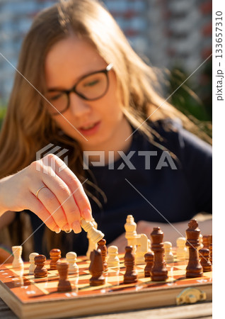 Caucasian woman playing chess outdoors. Caucasian woman playing chess outdoors. 133657310