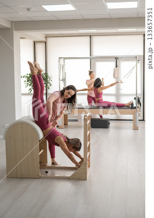 A trainer adjusts woman on a Ladder Barrel. A trainer adjusts woman on a Ladder Barrel. 133657351