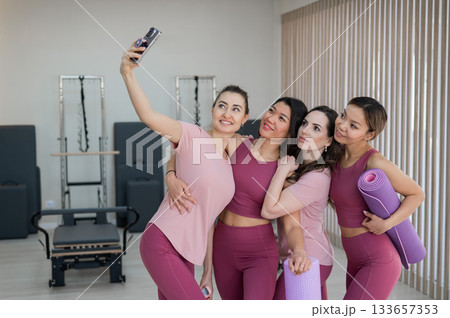 Two Caucasian and two Asian women take a selfie after a Pilates workout.  133657353