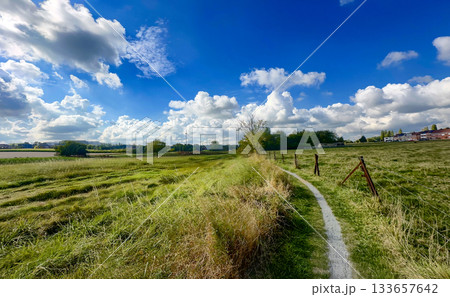 Open landscape with distant settlement under clear sky and clouds 133657642