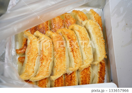 テイクアウト用パックに並んだ宇都宮餃子。きれいな焼き色とカリッとした質感が伝わる食品写真。 133657966