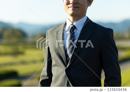 夕方の西日に当たるスーツを着たミドル男性ビジネスマン 夕方の西日に当たるスーツを着たミドル男性ビジネスマン 133658436