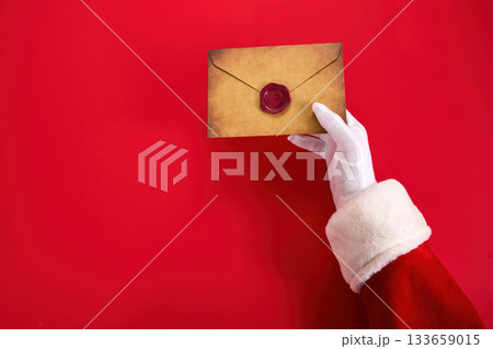 Santa's Letter. Santa's gloved hand holds a sealed letter Santa's Letter. Santa's gloved hand holds a sealed letter 133659015