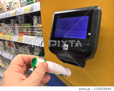 Shopping assistant scanning item at price checker in retail store 133659044