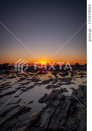 三浦市三崎町・高磯の岩礁に沈む夕日と静かな潮だまりの風景 133659064