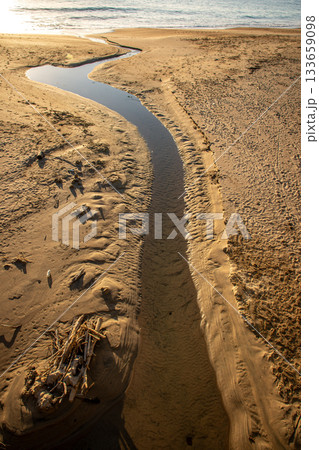 河原子海岸を流れる小川と朝日差し込む砂浜の風景（茨城県） 133659098