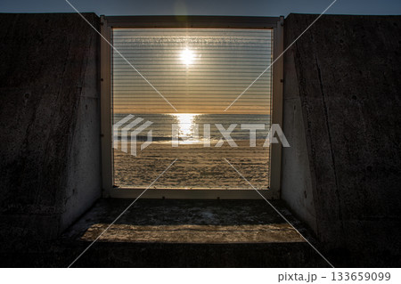 河原子海岸の防波堤越しに望む朝日と海の情景 133659099