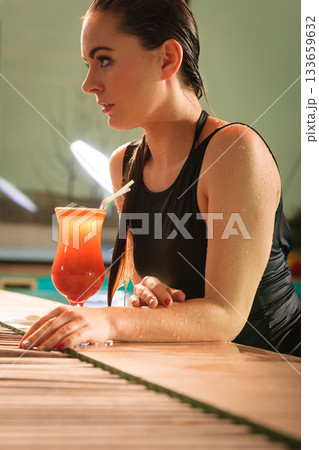 Woman with cocktail drink at swimming pool edge. Woman with cocktail drink at swimming pool edge. 133659632