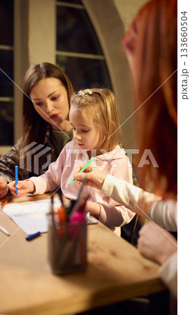 Woman guiding little girl during creative drawing session 133660504