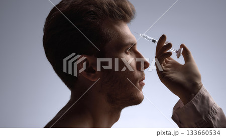 Specialist preparing forehead filler injection to soften expression lines 133660534