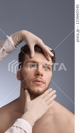 Specialist assessing male facial symmetry with guided hand placement Specialist assessing male facial symmetry with guided hand placement 133660540