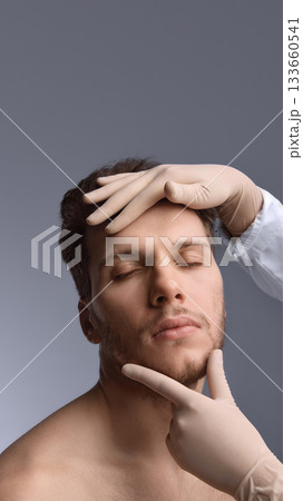 Doctor examining male face for aesthetic contour analysis Doctor examining male face for aesthetic contour analysis 133660541