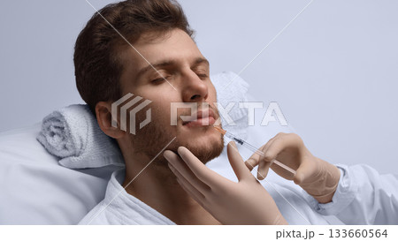 Close-up lip filler injection improving male lip symmetry. 133660564