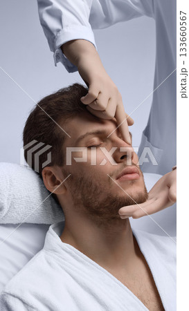 Doctor examining male nasal bridge and profile balance for rhinoplasty planning. 133660567