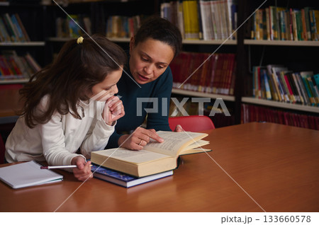 Mother And Daughter Reading Together In Library, Learning And Sharing Knowledge 133660578