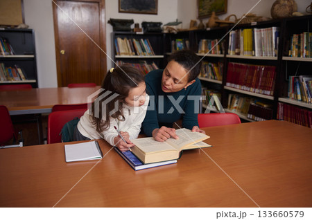 Teacher and Child Reading Together in Library During Study Session 133660579
