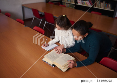 Teacher Helps Student Read in Library During Study Session, Fostering Learning and Focus 133660581