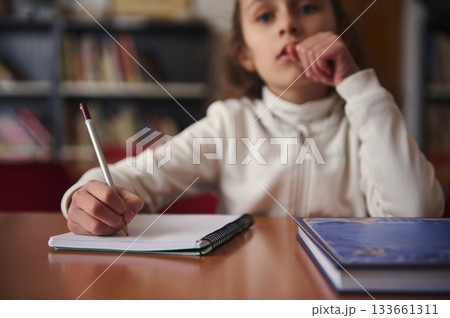 Child Writing in Library During Quiet Study Hour With Books Nearby 133661311