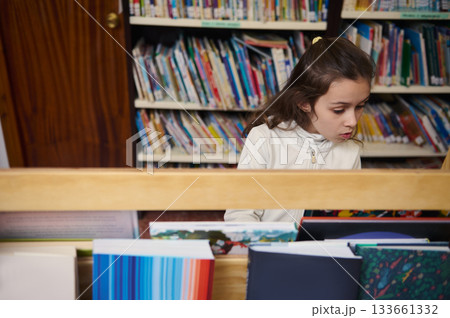 Young Girl Reading In A School Library Among Colorful Books And Shelves 133661332