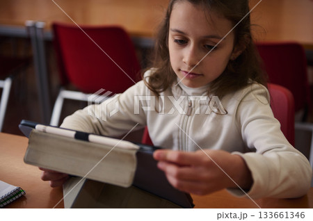 Young Girl Focused On Tablet In Library During Study Session At School 133661346