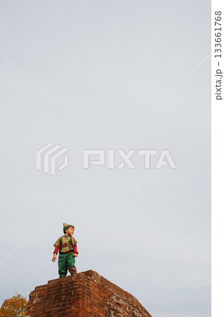 Child Dressed as Robin Hood Standing on Brick Wall 133661768