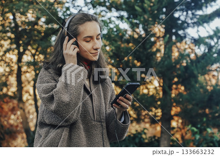 Young Woman Enjoying Music in Park During Autumn 133663232