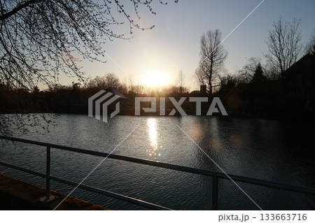 A calm lake with a fence on the side 133663716