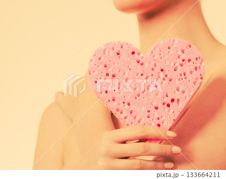 Naked woman holding heart sponge Naked woman holding heart sponge 133664211