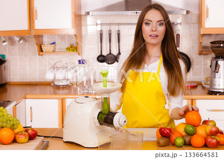 Woman in kitchen preparing fruits for juicing 133664581