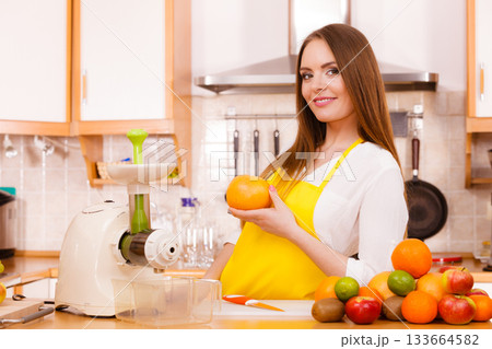 Woman in kitchen preparing fruits for juicing Woman in kitchen preparing fruits for juicing 133664582