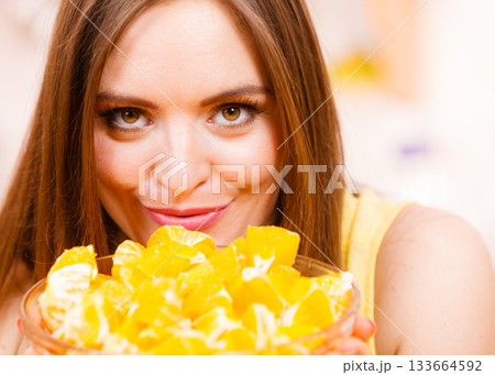 Woman holds bowl full of sliced orange fruits Woman holds bowl full of sliced orange fruits 133664592