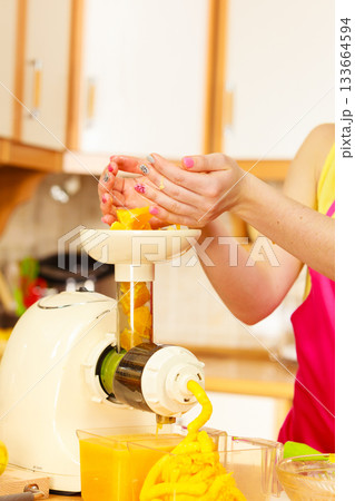 Woman making orange juice in juicer machine Woman making orange juice in juicer machine 133664594
