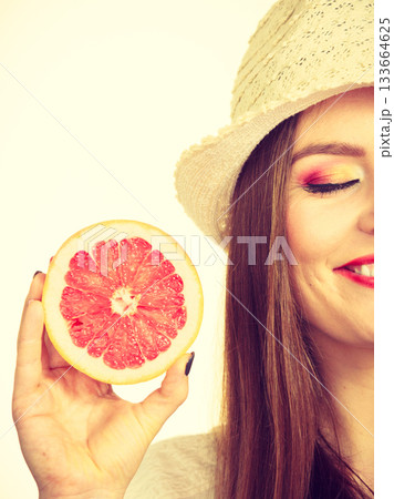 Woman holding half of grapefruit citrus fruit in hand Woman holding half of grapefruit citrus fruit in hand 133664625