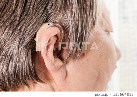 Closeup senior woman using hearing aid 133664815