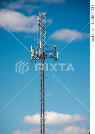 Tall cellular communication tower with antennas and radio equipment against bright blue sky Tall cellular communication tower with antennas and radio equipment against bright blue sky 133665335
