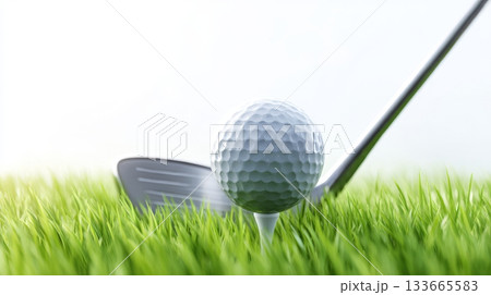 A shiny golf ball sits on a tee surrounded by fresh grass, with a club positioned nearby, ready for a swing on a sunny day 133665583